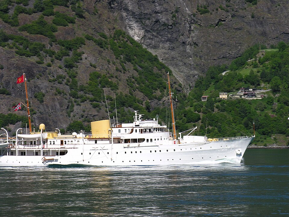 Kongeskipet «Norge» – hvitt skip i profil på fjorden med kongeflagget i toppen